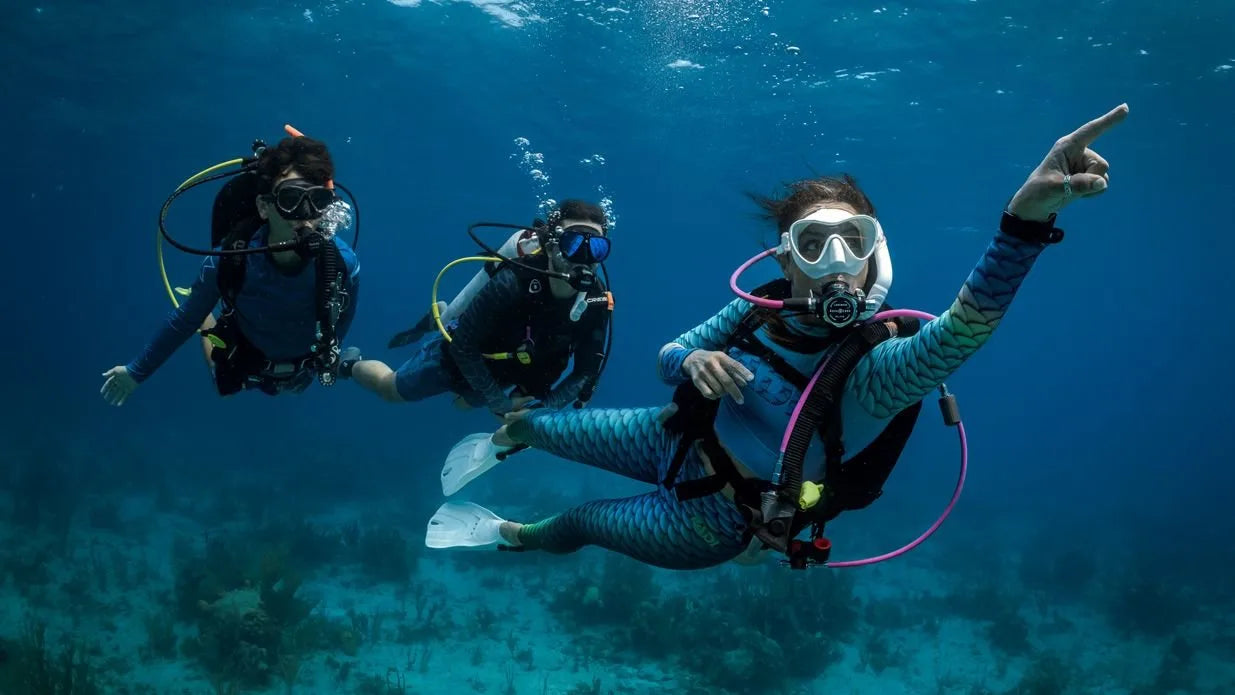 Three scuba divers underwater with clear blue water