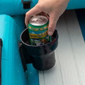 Hand placing a can into a black trash can on a blue surface