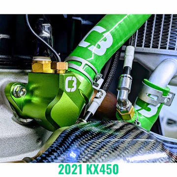 Close-up of a green motorcycle part with 'Husqvarna' branding, featuring the model number '2021 KX450'.