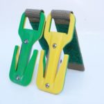 Two green and yellow metal clamps on a white background