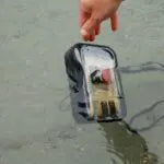 Person holding a fishing rod over water with a small boat nearby