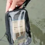 Person holding a small bag with a map on a muddy ground