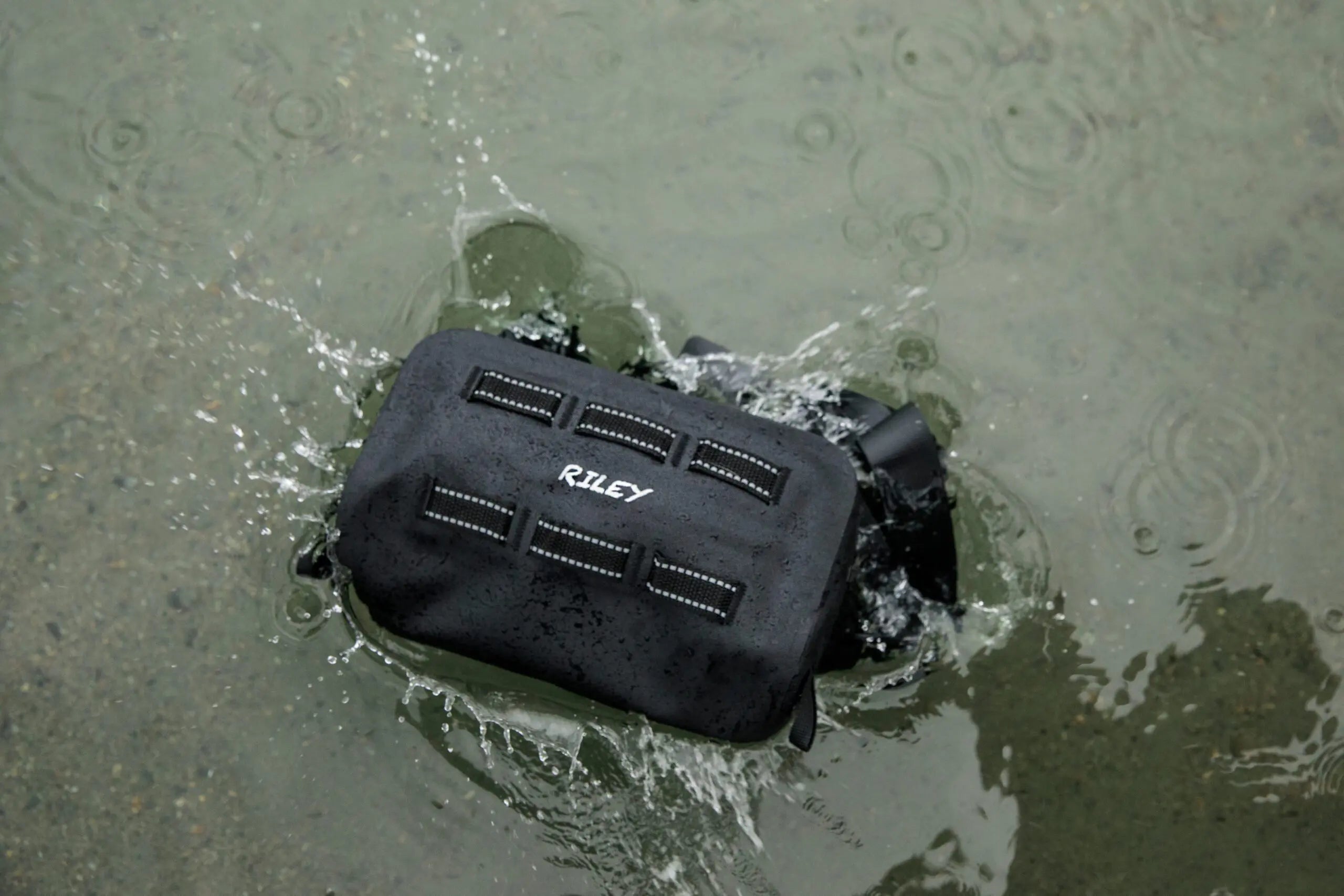 Black Riley bag submerged in water with visible water splashes.