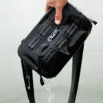Black leather bag held by a hand with visible brand logo.