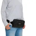 Person wearing a black waist bag on a plain background