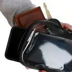 Person holding a black leather wallet with a strap
