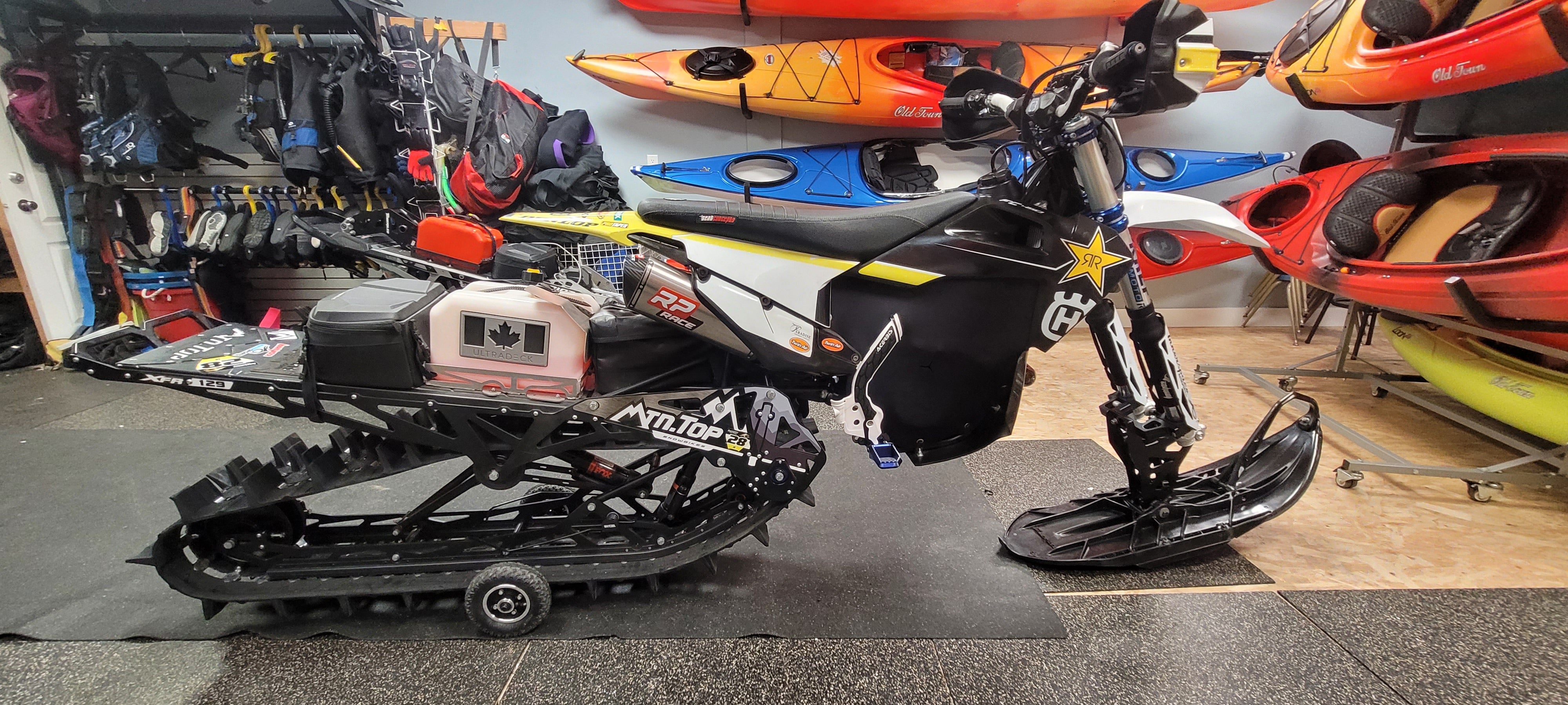 Snowmobile on display in a showroom with kayaks in the background