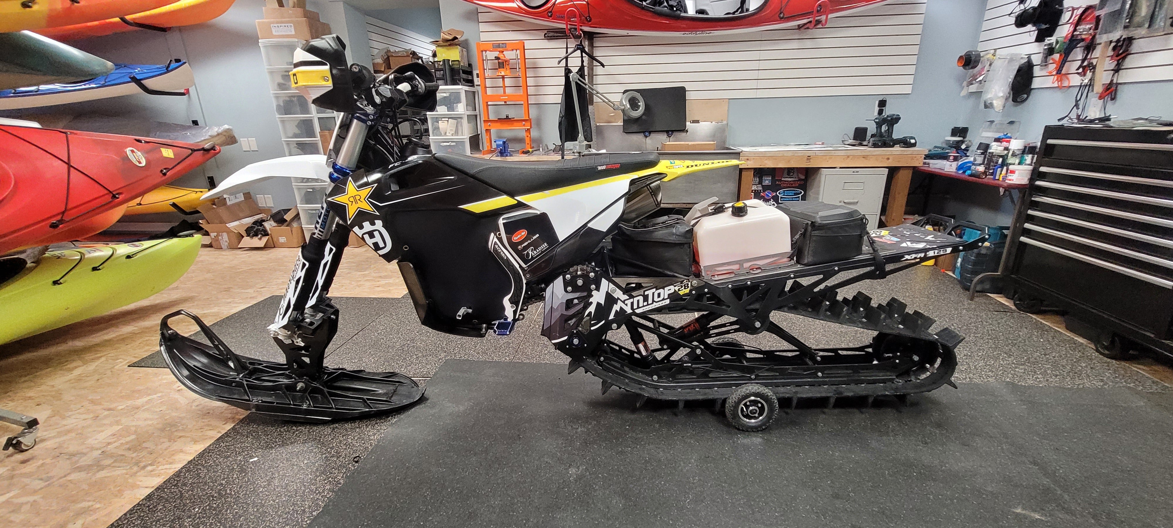 Black snowmobile with tracks in a workshop setting