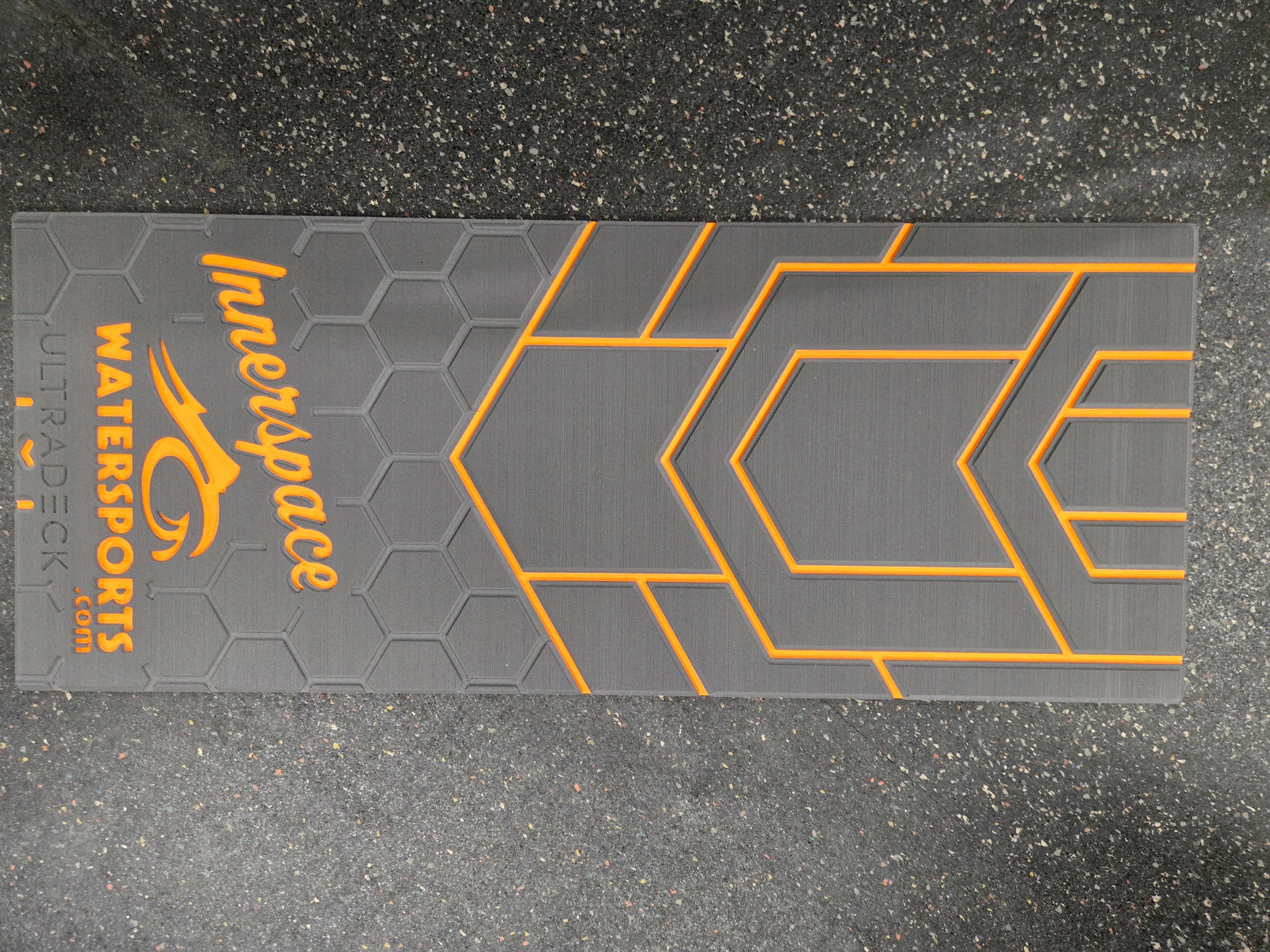 Gray watersports deck pad with orange geometric patterns and 'Innerspace Watersports' branding on a dark textured background.